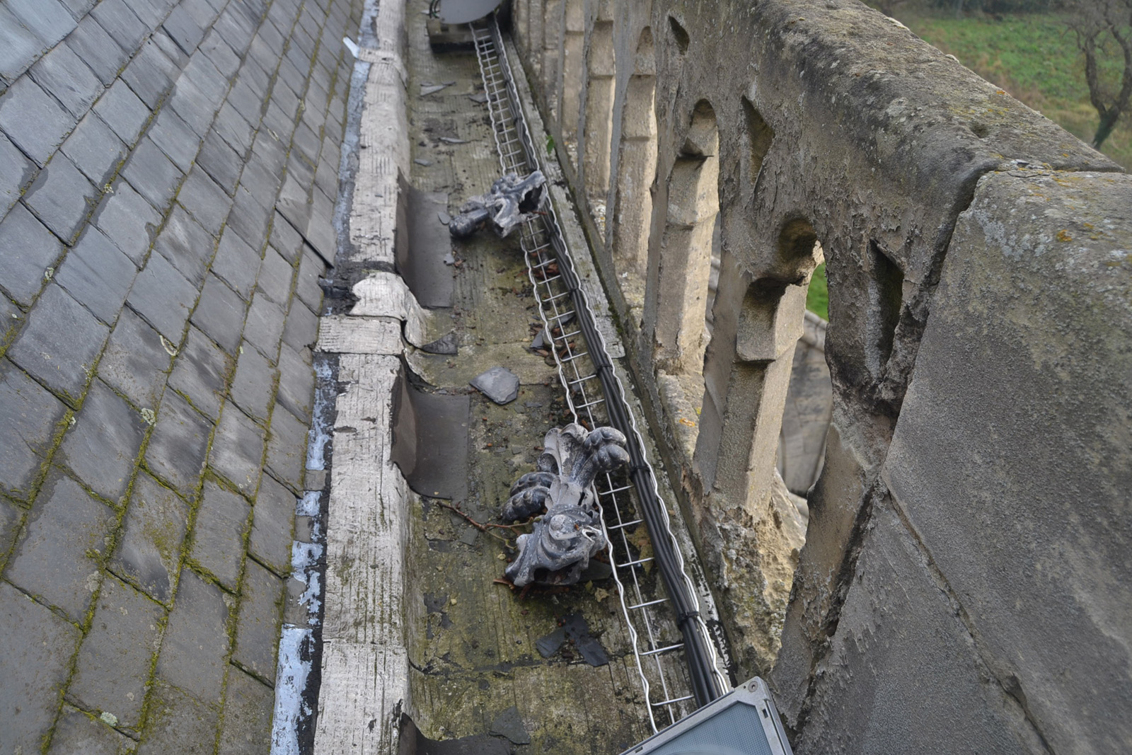 Vue des éléments décoratifs de faitage tombés dans le chéneau de toiture (2014)